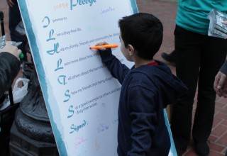 Youngster signs the Foundation for a Drug- Free World's drug-free pledge.