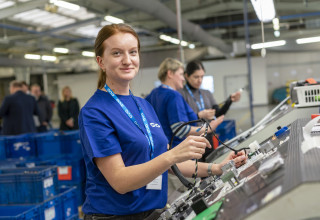 Ukrainian woman in CVG shirts assemblies electrical components in Czech Republic facility